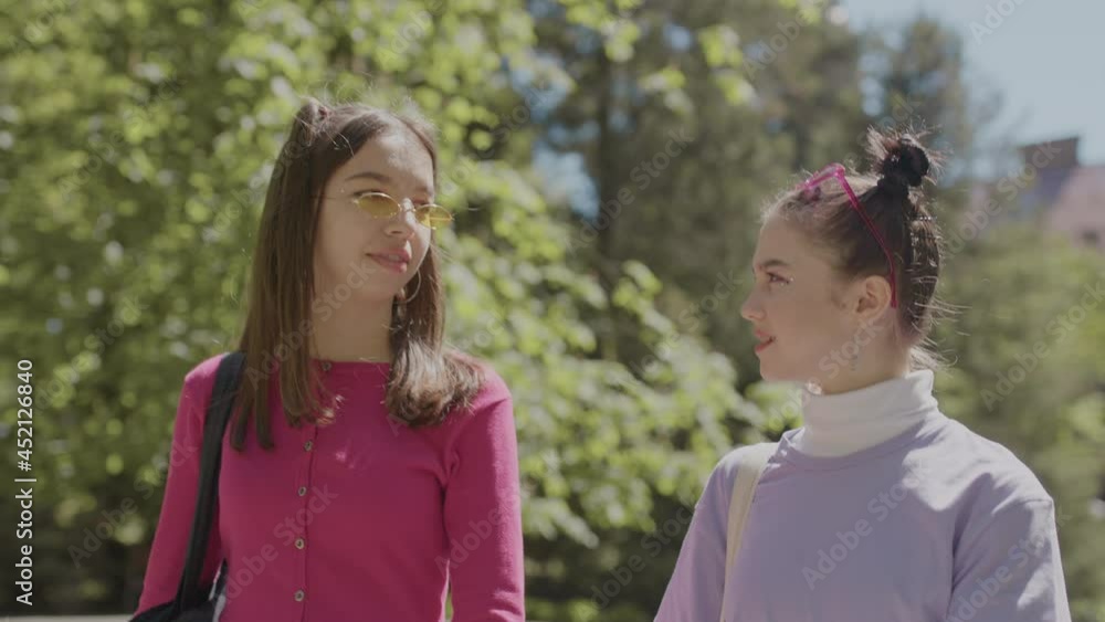 Two girlfriends walk in the park. Teenage girls in bright clothes. Two girlfriends walk in the park. Teenage girls in bright clothes.