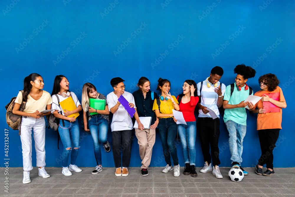 Obraz premium Group of happy multiracial teenage high school students talking and laughing before class. Back to school. Copy space