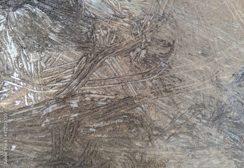 Excavator tracks on muddy soil aerial top down drone view for background.
