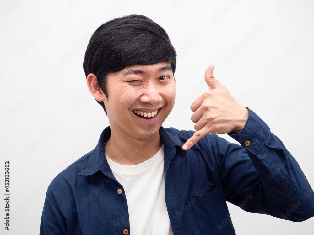 Cheerful man happy smile face gesture hand call mobile and close one eye portrait Cheerful man happy smile face gesture hand call mobile and close one eye portrait
