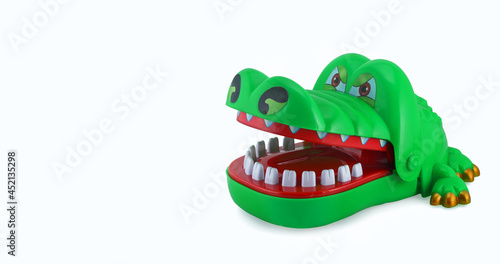 Green toy crocodile biting finger on white isolated background
