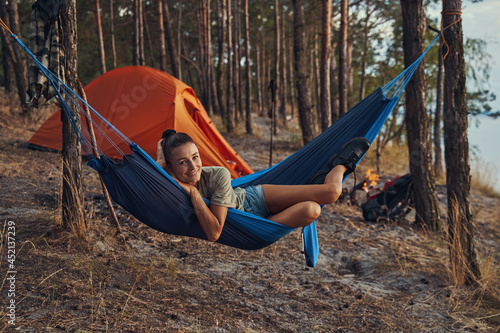 Camper chilling in her blue hammock near tent