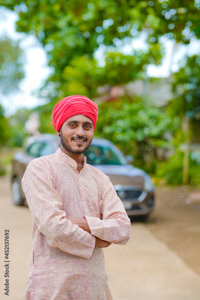 Fototapeta premium Young indian farmer standing his farmhouse.