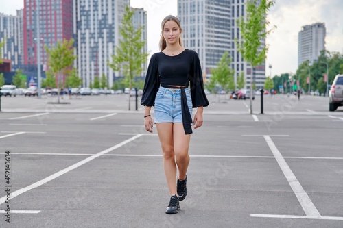 Running fashionable girl teenager, modern urban architecture parking background © Valerii Honcharuk