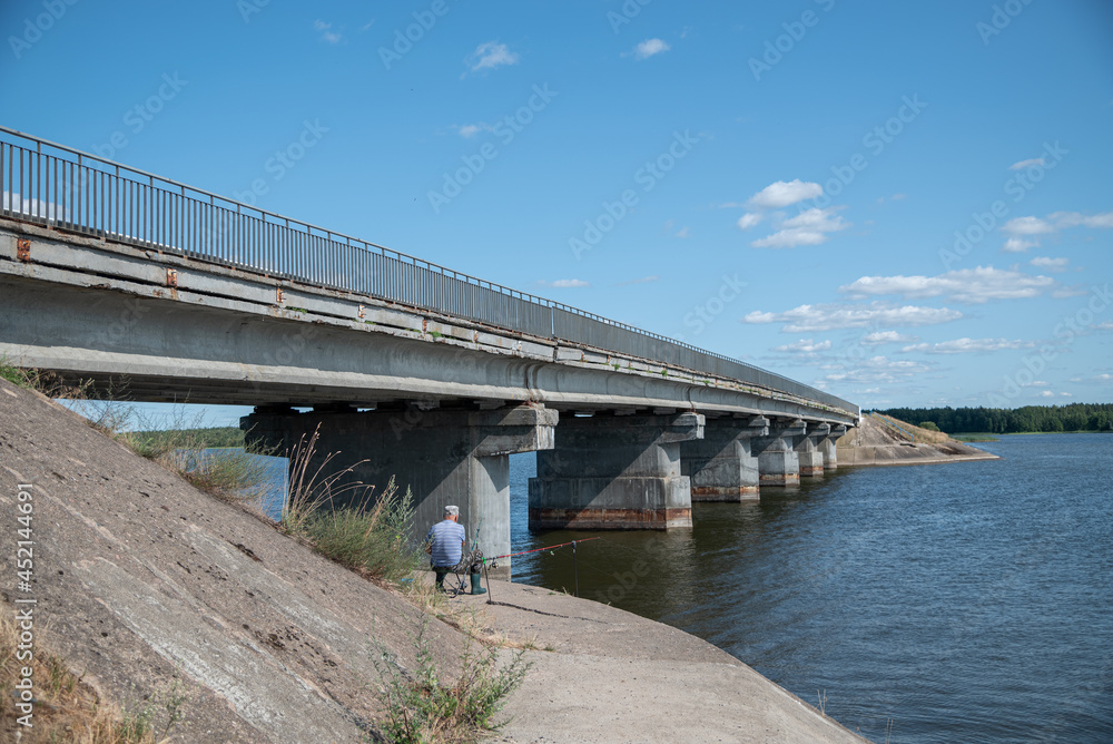Fisherman near the bridge over the Vileika reservoir Fisherman near the bridge over the Vileika reservoir