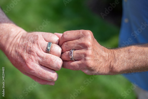 Two gay male senior citizens put their hands together to show off their wedding rings.