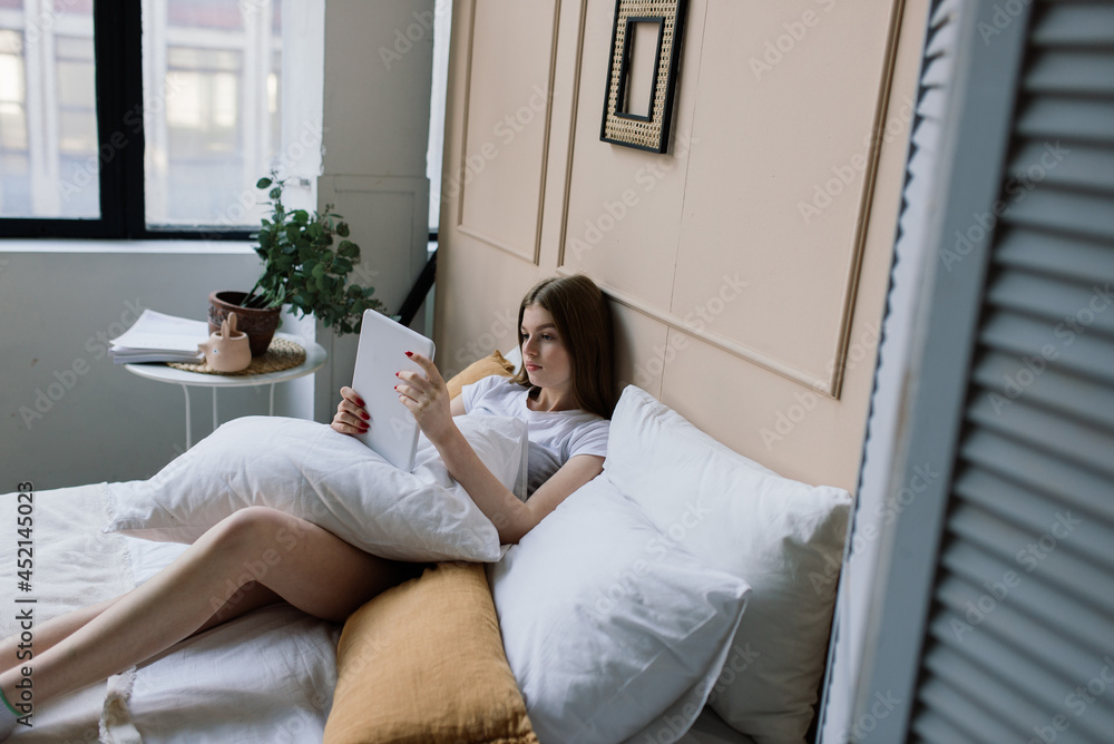Young attractive woman relaxing on white sofa at window at home Young attractive woman relaxing on white sofa at window at home
