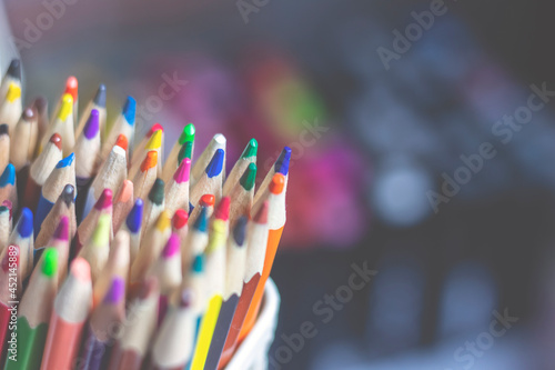 There are a lot of colored pencils standing vertically in a stationery stand. A set for fine art.