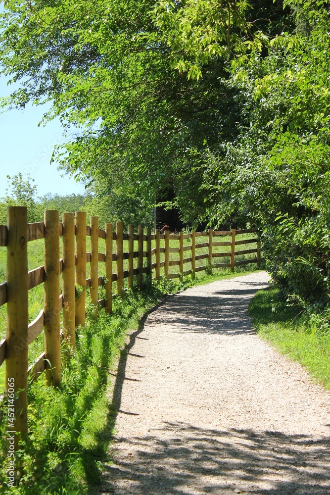 An old country wooden fence following a gravel road around a bend in the rural country.