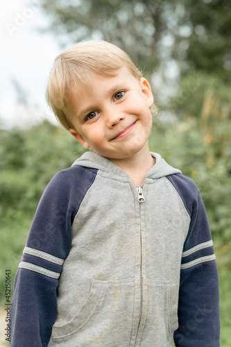 portrait of a cute little four year old smiling happy candid european kid boy in nature in the garden in summer