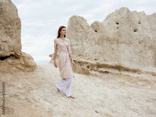 pretty woman posing near rocks in the sand attractive look