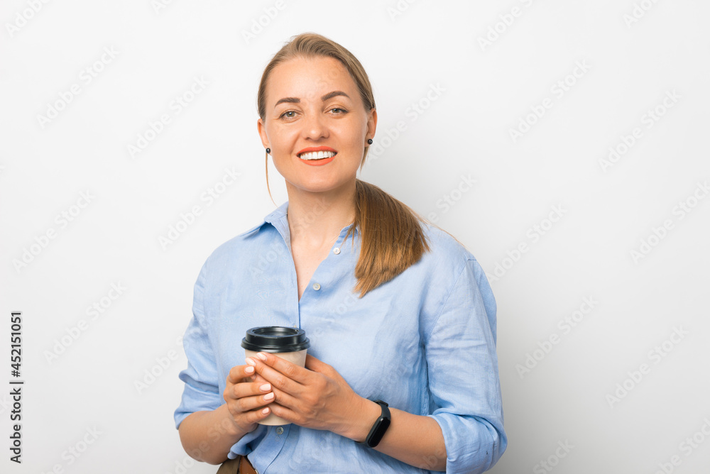 Young blonde lady smiling at the camera is holding a take away cup of coffee. Young blonde lady smiling at the camera is holding a take away cup of coffee.