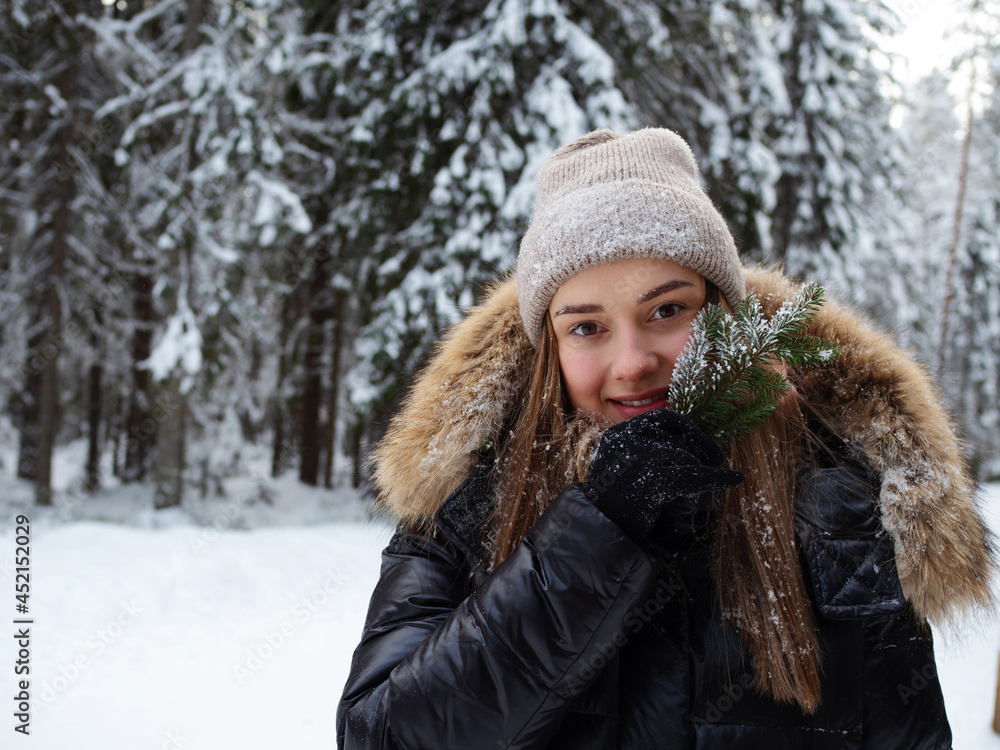 A happy smiling woman in warm clothes holds a coniferous twig in her hand. A happy smiling woman in warm clothes holds a coniferous twig in her hand.