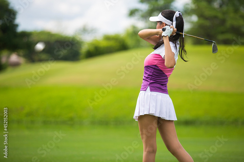 Asian girls are playing golf on a sunny day on the beautiful green golf course.