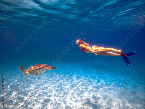 Free diver woman with blue fins underwater swimming with wild turtle in sea in Cyprus, ocean lover, snorkelling