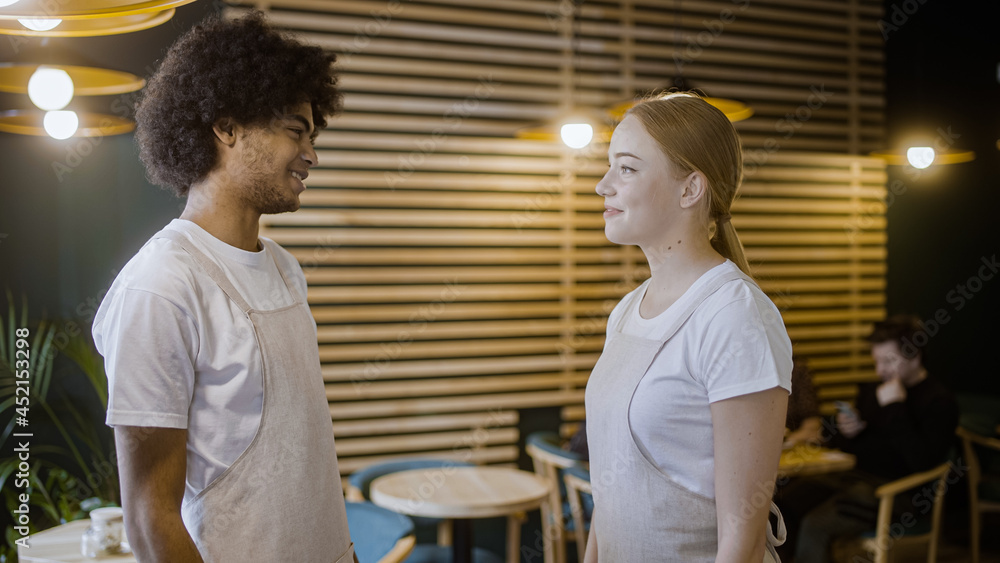 Happy male and female waiters smiling and talking at work in restaurant, team Happy male and female waiters smiling and talking at work in restaurant, team