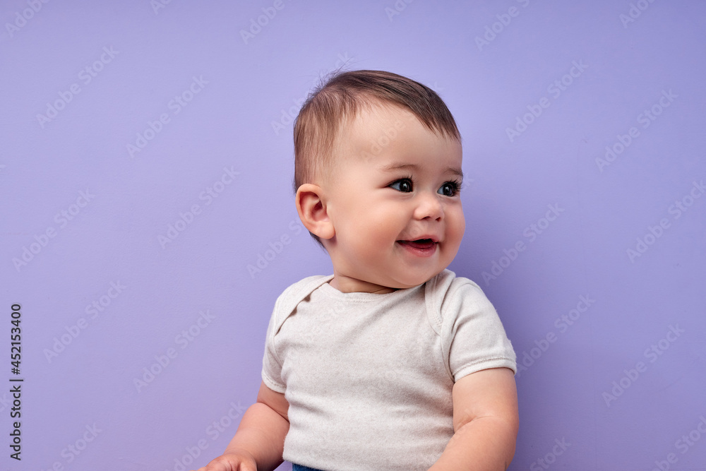 child is smiling enjoying adopted life. Concept of happy family or successful adoption or parenting. Little baby in casual wear looking at side enjoying, sweet child isolated over purple background child is smiling enjoying adopted life. Concept of happy family or successful adoption or parenting. Little baby in casual wear looking at side enjoying, sweet child isolated over purple background