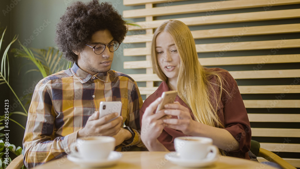 Girlfriend showing boyfriend new mobile app on smartphone, friends talking about gadgets Girlfriend showing boyfriend new mobile app on smartphone, friends talking about gadgets