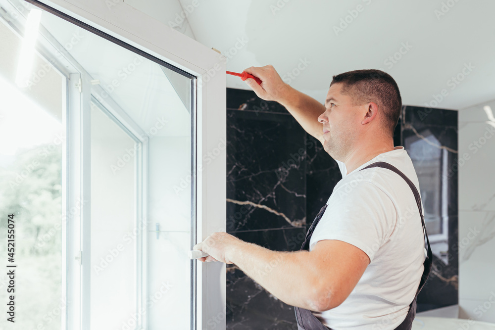 The worker adjusts the window in the apartment of the house after repair The worker adjusts the window in the apartment of the house after repair