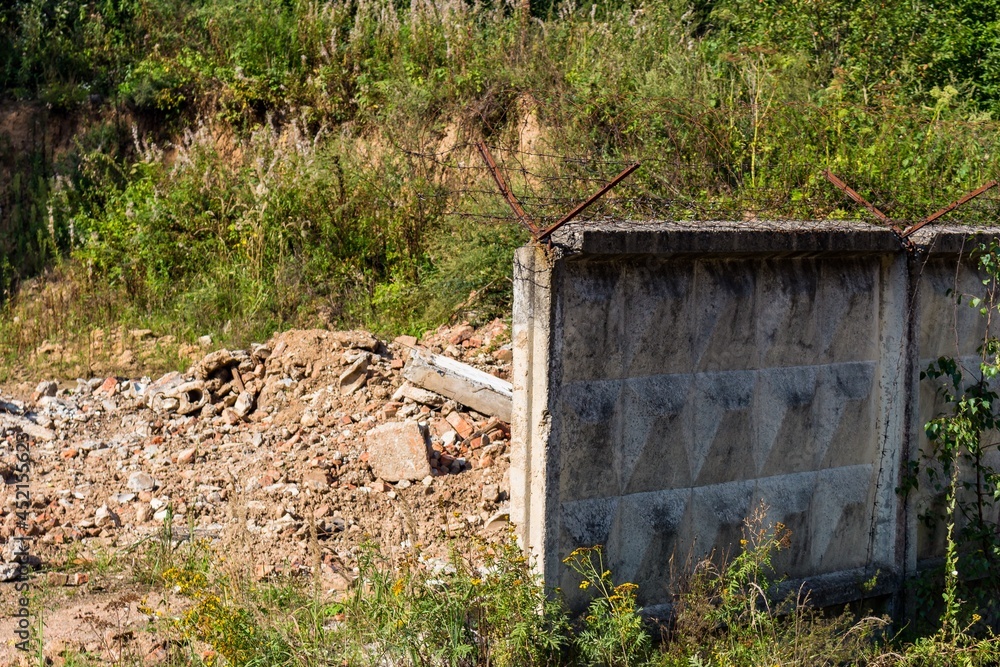 Remains of a destroyed building and a broken fence with barbed wire on the territory of a military unit from the times of the USSR, Russia Remains of a destroyed building and a broken fence with barbed wire on the territory of a military unit from the times of the USSR, Russia