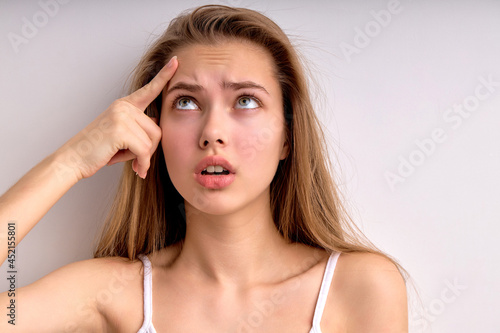 Frustrated young female feeling stressed upset about facial skin problem concept wrinkles or pimple, worried depressed lady touch skin on forehead annoyed by acne, close-up portrait. copy space