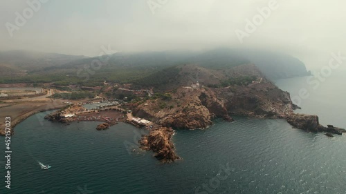 Aerial drone point of view Lastre Playa in the spanish town of Portman. Cloud sky over mountains, beach with crowd of people enjoy summer holidays. Murcia region, Cartagena, Costa Calida, Spain photo