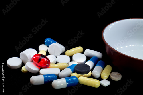 pills of different shapes and colors on a black background. macro photo