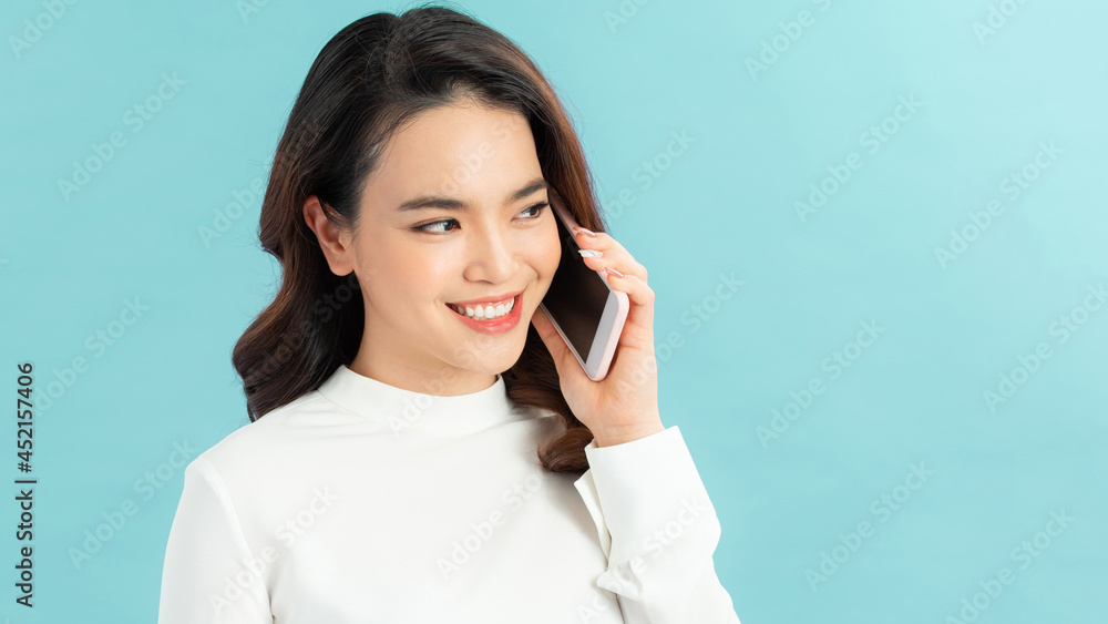 Smiling woman talking on the phone isolated on a blue background Smiling woman talking on the phone isolated on a blue background