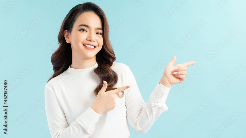 Happy beautiful young woman showing pointing to the side with fingers isolated on blue background. Happy beautiful young woman showing pointing to the side with fingers isolated on blue background.
