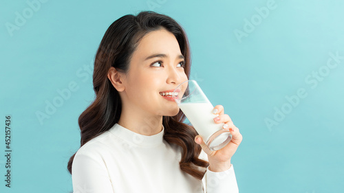 young woman drink glass of milk, female happy smile, isolated on blue background natural organic concept