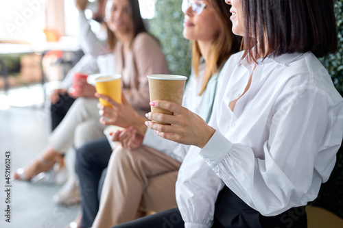 business  communication and education concept. group of colleagues drinking coffee during break time  close-up photo of woman hands sitting with cup  having talk or listening  in formal wear