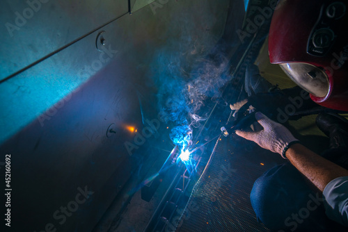Closeup of metal welder is working with arc welding machine to weld steel for assembly structure of machine in construction site.