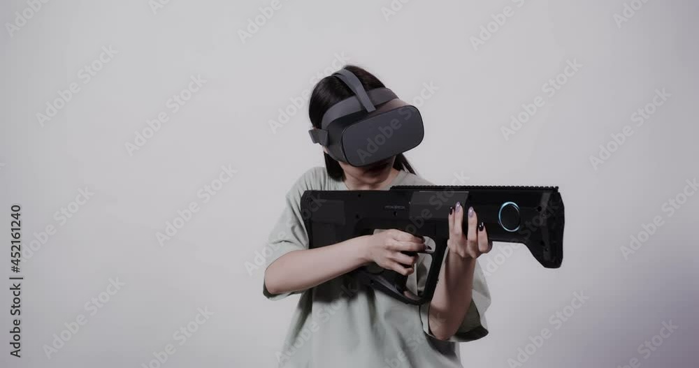 Asian girl in virtual reality glasses with toy weapon plays in a 5D attraction Asian girl in virtual reality glasses with toy weapon plays in a 5D attraction