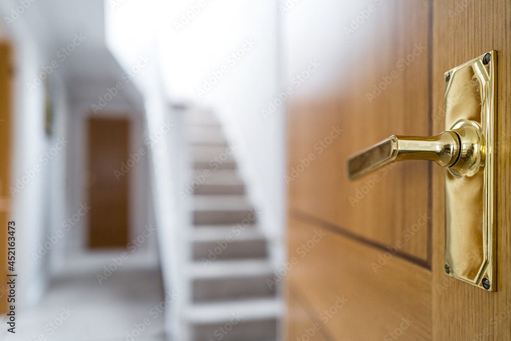 Shallow focus of a gold-coloured internal door handle seen in a lobby area of a large, evenly built home. Shallow focus of a gold-coloured internal door handle seen in a lobby area of a large, evenly built home.