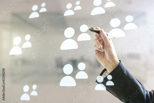 Double exposure of man hand with pen working with abstract virtual social network icons on blurred office background. Marketing and promotion concept