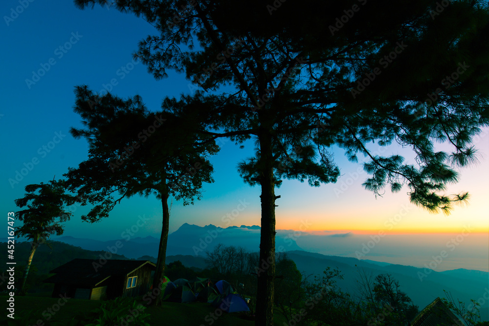 Obraz premium Colorful sky at the morning over mountains in north of Thailand with tents and house at top of mount
