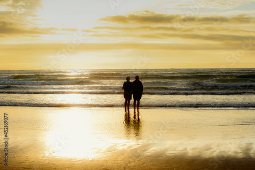 Romantic senior couple of retirement age looking out to sea at sunset