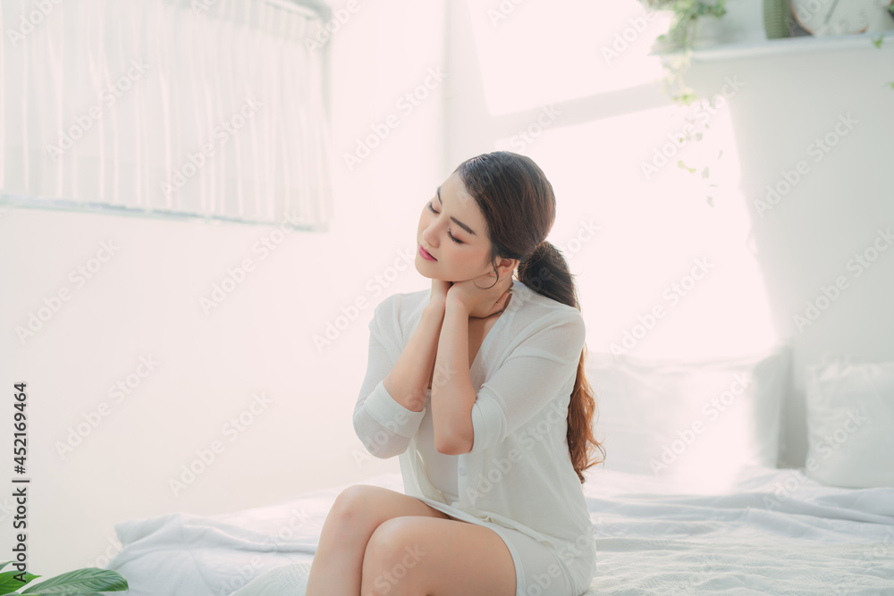 Adult attractive dreamy lady touching neck sitting bed Adult attractive dreamy lady touching neck sitting bed