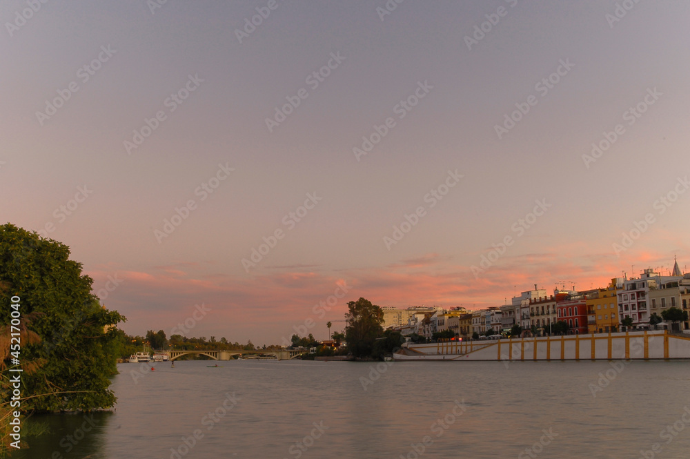 River and houses in the evening with colorful clouds | Seville, Spain