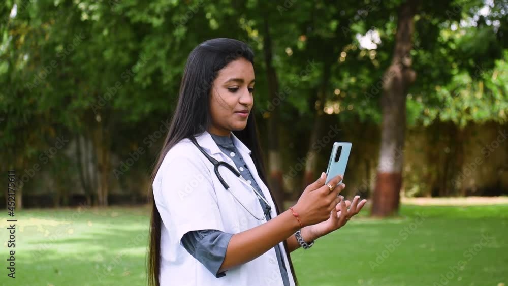 Portrait video of young Indian female doctor providing medical aid remotely, looking at camera and talking to clinic patient through video call app. Modern tech, medicine, telemedicine Portrait video of young Indian female doctor providing medical aid remotely, looking at camera and talking to clinic patient through video call app. Modern tech, medicine, telemedicine