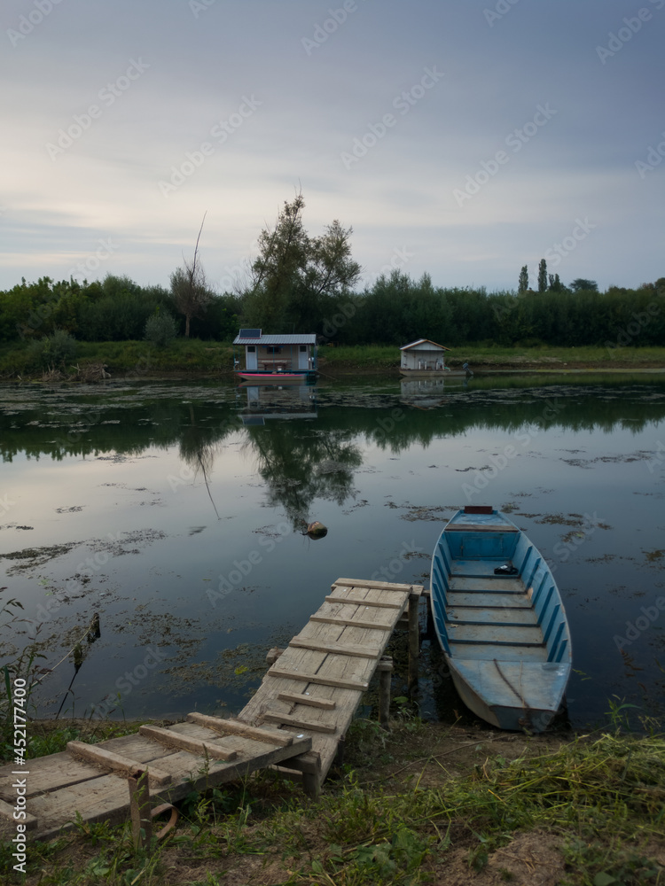 Landscape of Sava river with fishing boats and huts during summer overcast day