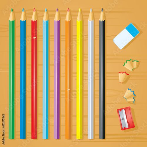 A set of coloring pencils - with eraser, parer and pencil parings - on a wooden desktop
