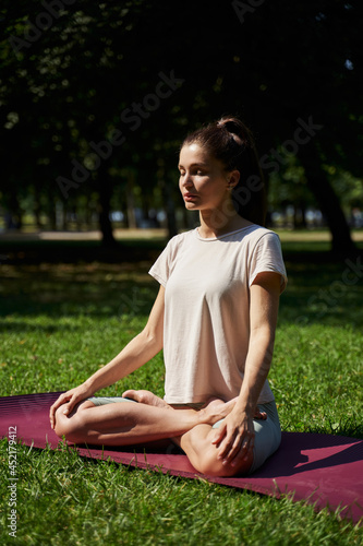 woman meditates in the park. woman in the park doing yoga. pilates, gymnastics in the summer. sport exercises. young sports woman.