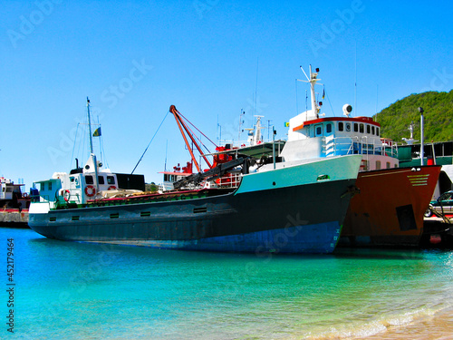 A tug and a cargo ship docked in Bequia, St Vincent and the Grenadines, Caribbean lesser Antilles.