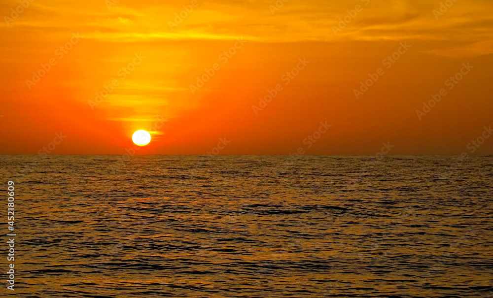 Sunset at sea, calm ocean and red, pink and orange sun glow.