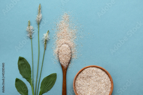 Billede på lærred Psyllium plant product is the husk of plantain seeds in a plate and a wooden spoon on a blue background