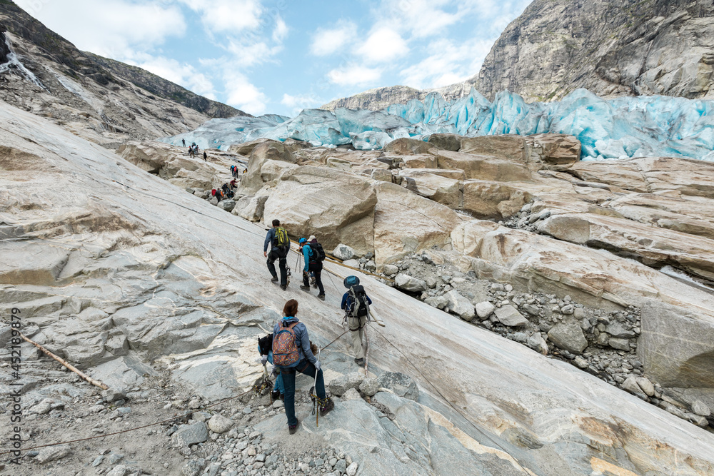 Tourists are climbing rock surface of Jostedal Glacier