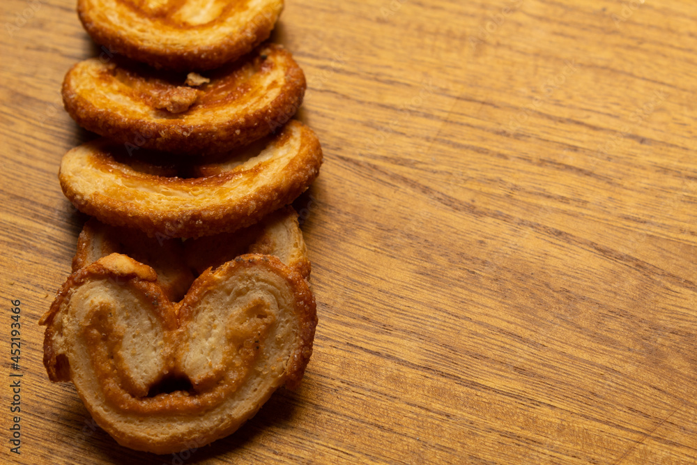 close up of many delicious freshly baked puff pastry ears on a wood colored board close up of many delicious freshly baked puff pastry ears on a wood colored board