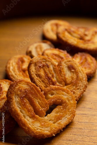 close up of many delicious freshly baked puff pastry ears on a wood colored board
