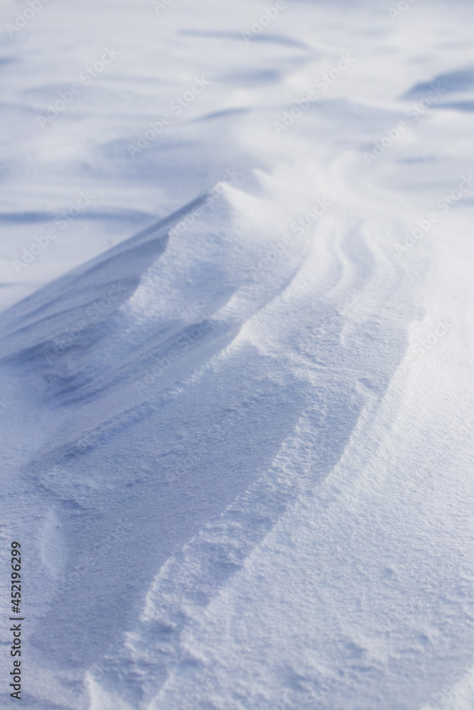 Snowy background, snow-covered surface of the earth after a blizzard in the morning in the sunlight with distinct layers of snow